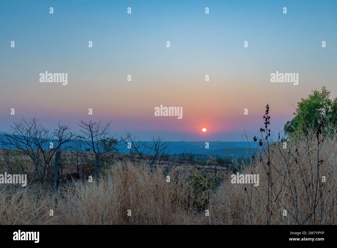 Un coucher de soleil sur une montagne. Les rayons du soleil qui brillent sur les sommets créent une gamme de couleurs, allant des oranges chaudes et jaunes aux violets et bleus frais. Banque D'Images