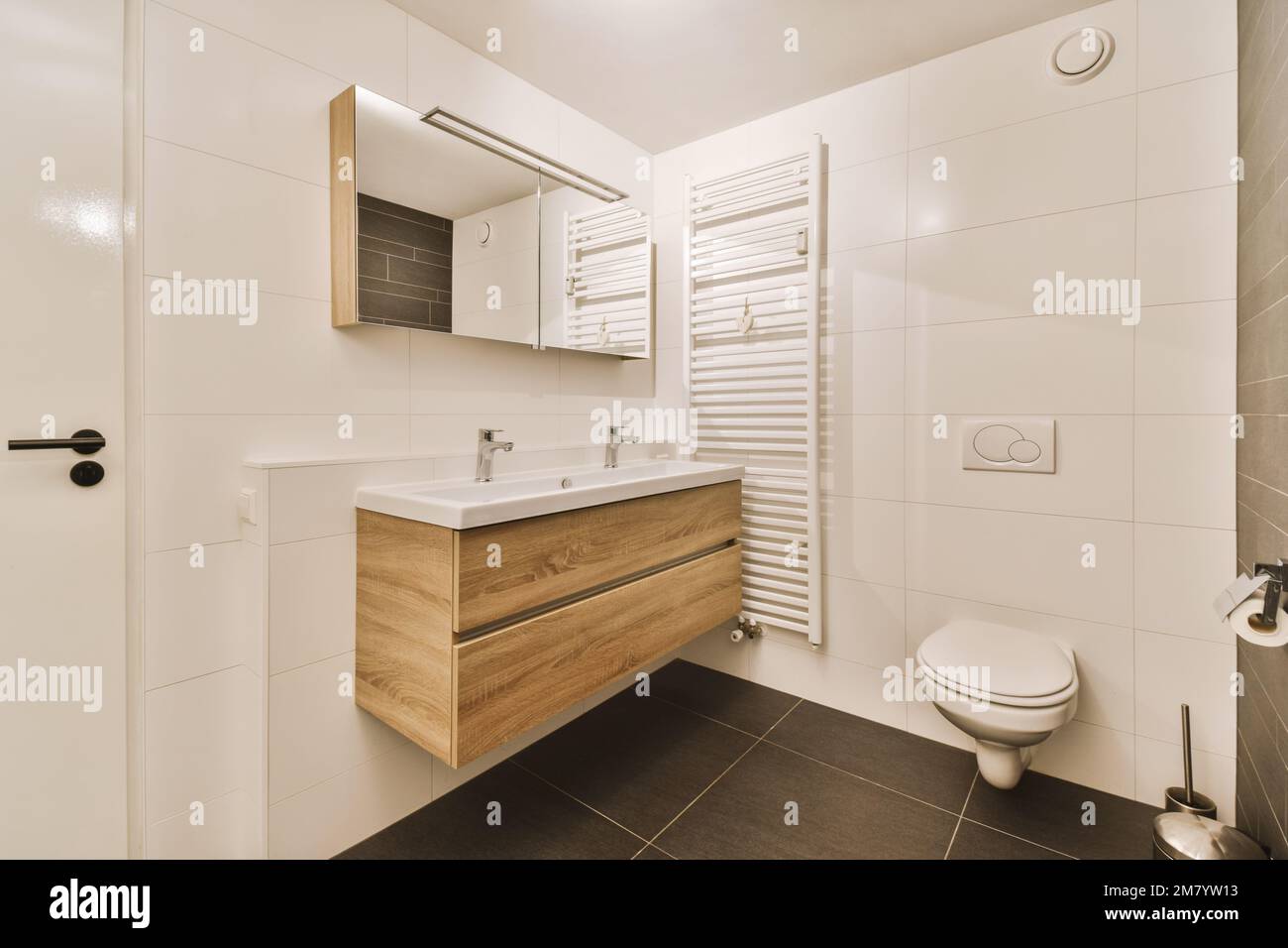 salle de bains moderne avec carrelage noir, carrelage blanc sur les murs, meuble-lavabo en bois Banque D'Images