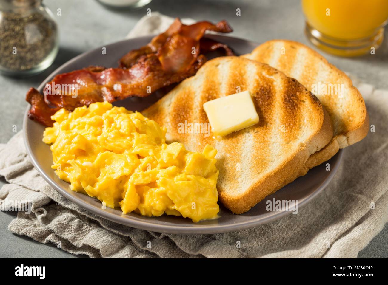 Petit-déjeuner américain aux œufs brouillés maison avec bacon et pain grillé Banque D'Images