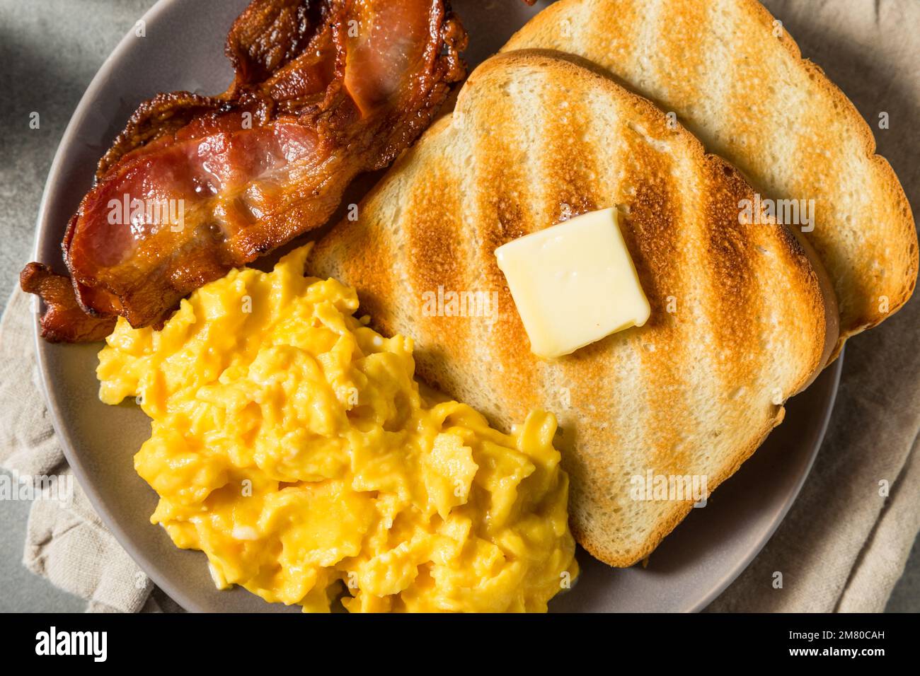 Petit-déjeuner américain aux œufs brouillés maison avec bacon et pain grillé Banque D'Images