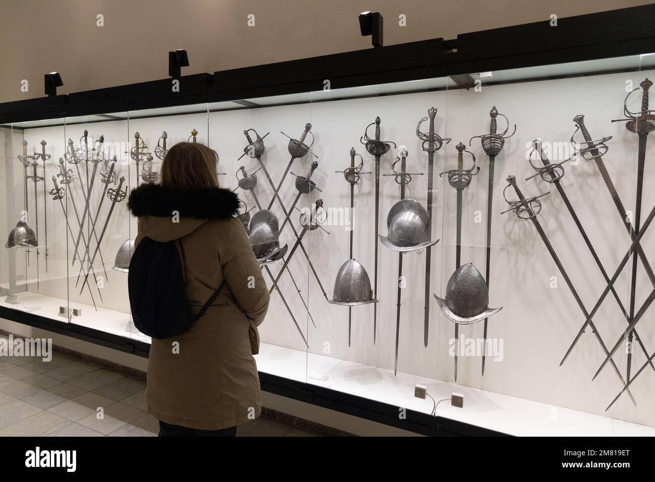 Un visiteur regardant les armes de guerre médiévale comprenant des épées et des casques; intérieur du musée du château de Wawel, Cracovie Pologne Europe Banque D'Images