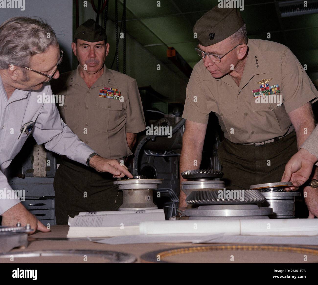 W. P. Miller, à gauche, contremaître, atelier de grue électrique, Division des réparations, Explique une partie de la transmission du véhicule d'atterrissage, à chenilles (LVT7), au général P. X. Kelly, commandant du corps des Marines. Le major général R. A. Shaffer, au centre, commandant général, base de logistique du corps des Marines, est à l'affût. Base: Corps de la marine base de Logis, Albany État: Géorgie (GA) pays: Etats-Unis d'Amérique (USA) Banque D'Images