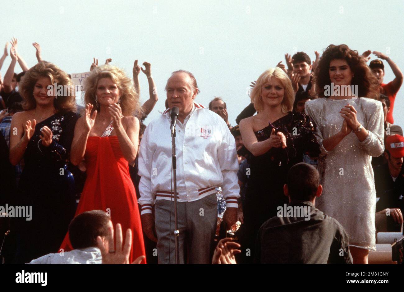 L'artiste Bob Hope joue pour les hommes d'équipage à bord du cuirassé USS NEW JERSEY (BB-62) avec l'aide de, de gauche à droite: Miss U.S.A. Judy Hyek, Cathy Lee Crosby, Ann Jillian et Brooke Shields, lors d'un spectacle USO de la veille de Noël. Le NEW JERSEY opère au large de la côte de Beyrouth, au Liban. Pays: Mer méditerranée (MED) Banque D'Images