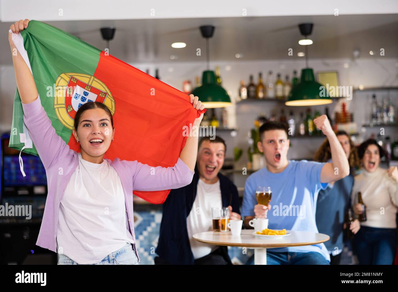 Compagnie de jeunes fans de sports adultes hurlant le drapeau du Portugal et soutenant l'équipe nationale avec de la bière dans le pub Banque D'Images