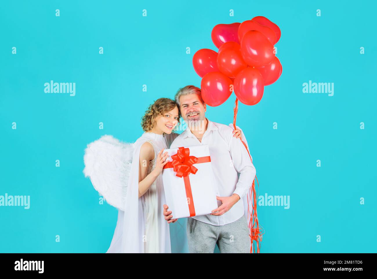 Saint-Valentin couple avec ailes blanches. Cupid ange femme avec ballons et barbu homme avec cadeau. Banque D'Images