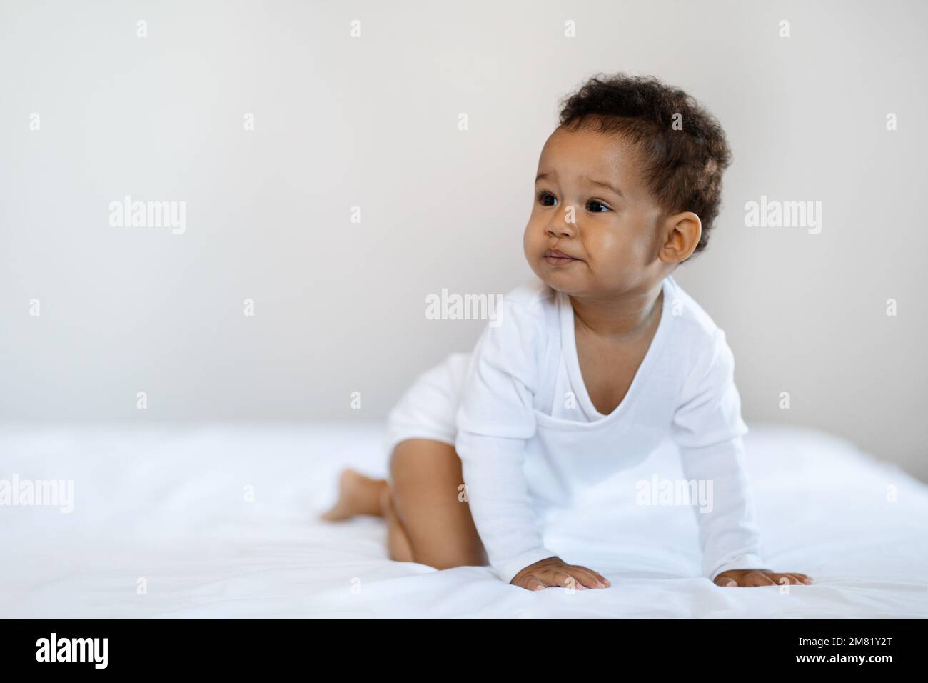 Garde d'enfants. Bébé noir garçon ou fille rampant sur le lit à la maison Banque D'Images