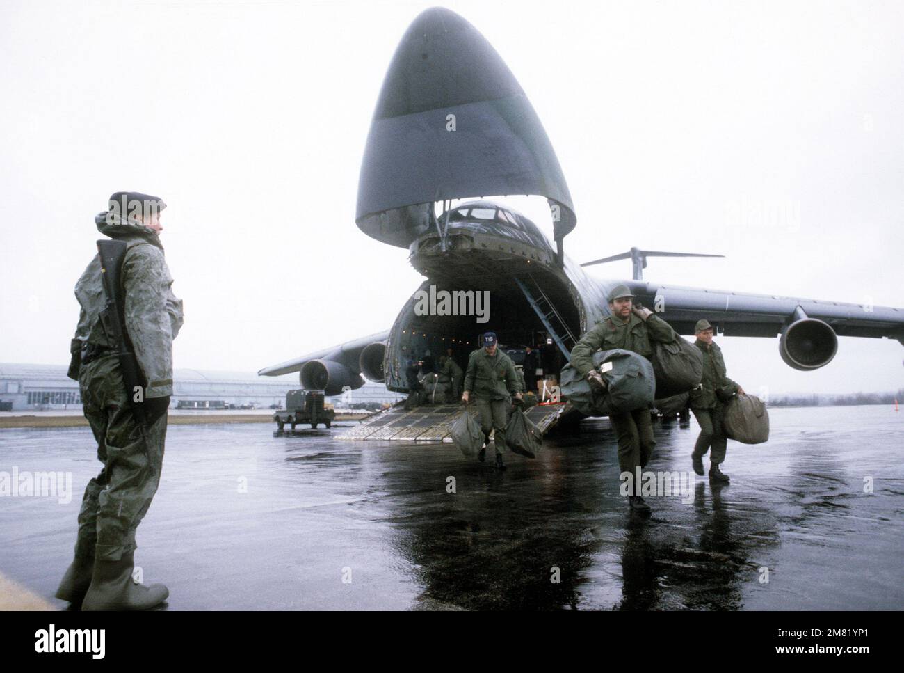 Un policier de sécurité du Commandement aérien stratégique du quartier général se tient à côté de l'équipement qui est déchargé d'un avion C-5 Galaxy pendant l'exercice GLOBAL SHIELD '84. Opération du sujet/série : GLOBAL SHIELD '84 base : Offutt Air Force base État : Nebraska (ne) pays : États-Unis d'Amérique (USA) Banque D'Images
