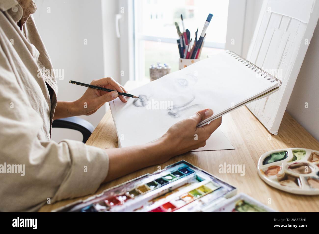 Femme apprenant comment dessiner à la maison tenant crayon Banque D'Images