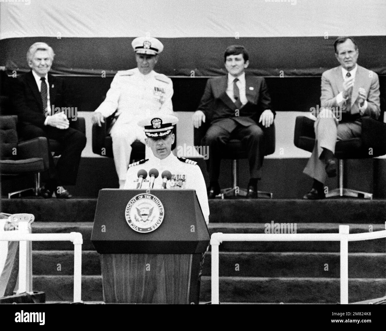 Le capitaine Gerald Gndow, commandant de l'USS IOWA (BB 61), prend la parole au cours de la cérémonie de mise en service du cuirassé. Assis derrière lui, de droite à gauche : le vice-président George H. Bush, le secrétaire de la Marine John F. Lehman Jr., l'amiral Wesley McDonald, commandant en chef de la flotte de l'Atlantique des États-Unis. C'est la troisième fois que l'IOWA est mis en service. Base: Pascagoula État: Mississippi (MS) pays: Etats-Unis d'Amérique (USA) Banque D'Images