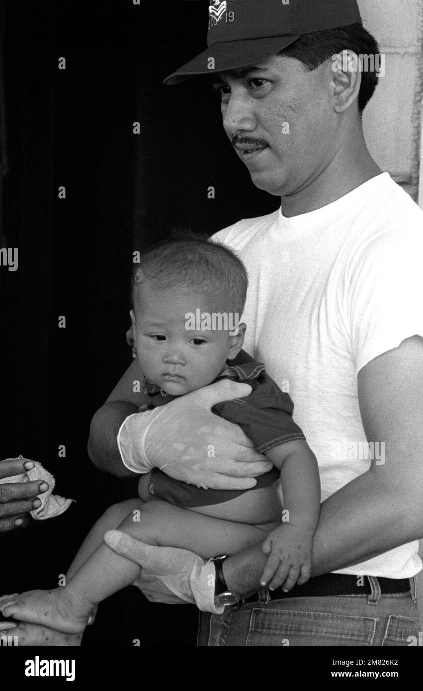 MAÎTRE à Arms First Class Jose Morillo tient un bébé, l'un des 35 réfugiés vietnamiens secourus par le navire de commandement amphibie USS BLUE RIDGE (LCC 19) à 350 miles au nord-est de Cam Ranh Bay, Vietnam. Ils avaient passé huit jours en mer dans un bateau de pêche de 35 pieds. Base: USS Blue Ridge (LCC 19) pays: Mer de Chine méridionale Banque D'Images