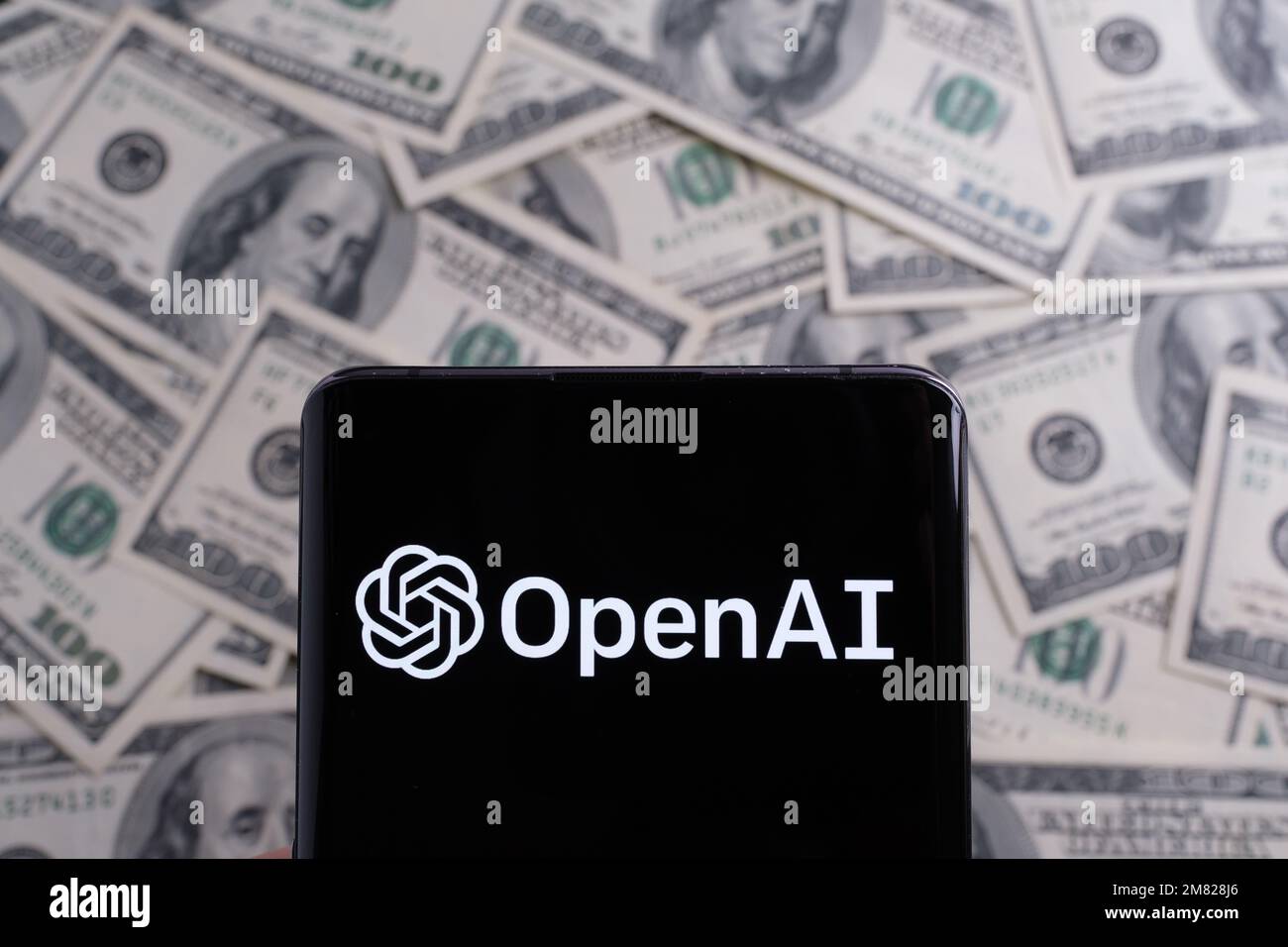 Logo OPENAI vu sur smartphone et dollars US flous sur fond. Concept. Stafford, Royaume-Uni, 11 janvier 2023 Banque D'Images