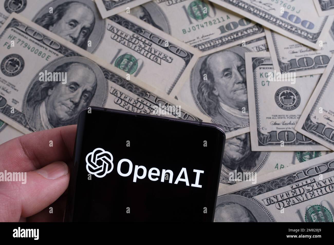 Logo OPENAI vu sur smartphone et dollars US flous sur fond. Concept. Stafford, Royaume-Uni, 11 janvier 2023 Banque D'Images