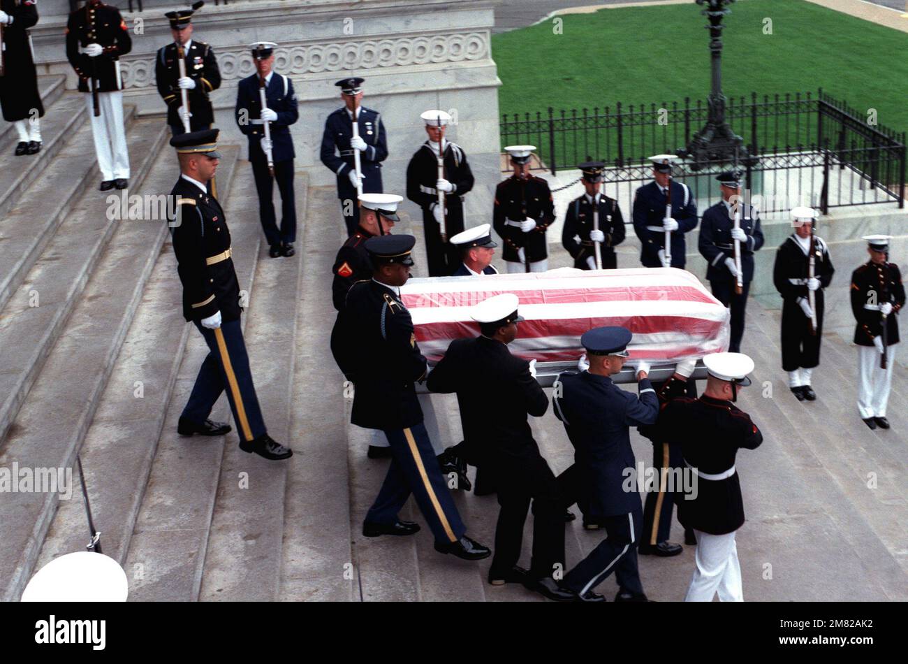 Une équipe de cercueils de services communs porte le cercueil à pavillon du  Serviceman inconnu de l'époque du Vietnam hors de la rotonde et le long des  marches est du Capitole. Un