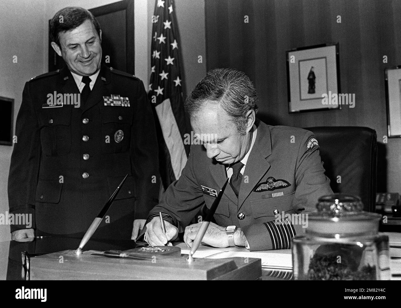 Le Capt de groupe Alan W. Thurecht, directeur des mouvements et des transports, ministère de la Défense, Australie (à gauche), signe des procédures de travail détaillées pour l'Entente de transport aérien coopératif entre le Commandement du transport aérien militaire (MAC) et l'Australie. On y regarde col Clarence H. Lindsey, Jr., chef de cabinet adjoint, transport aérien pour MAC. Base: Scott Air Force base État: Illinois (il) pays: États-Unis d'Amérique (USA) Banque D'Images