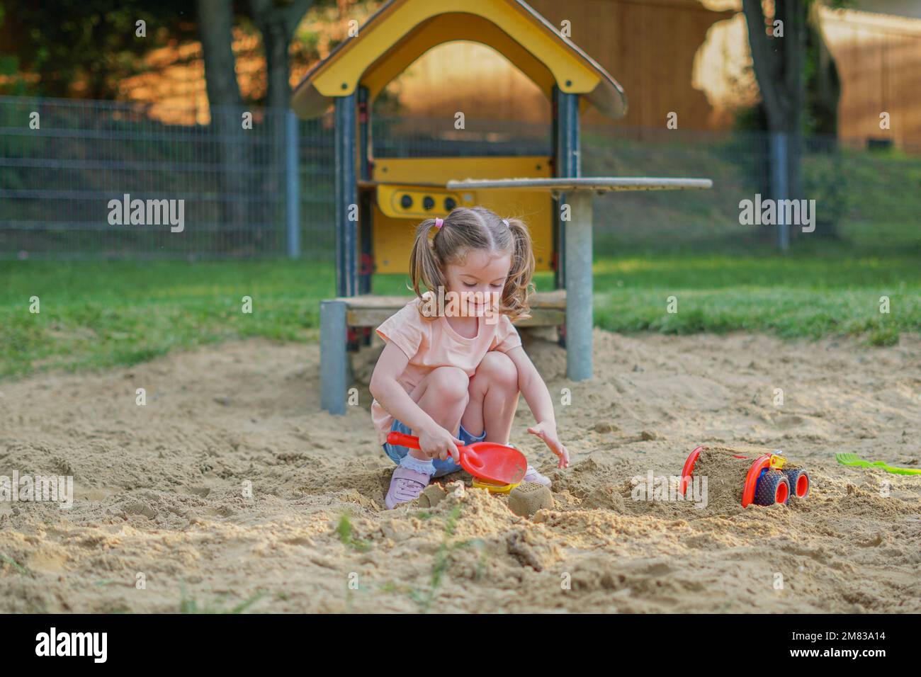 Beau bébé s'amuser un jour ensoleillé d'été chaud - petite fille mignonne jouant dans le sable sur l'aire de jeux extérieure Banque D'Images