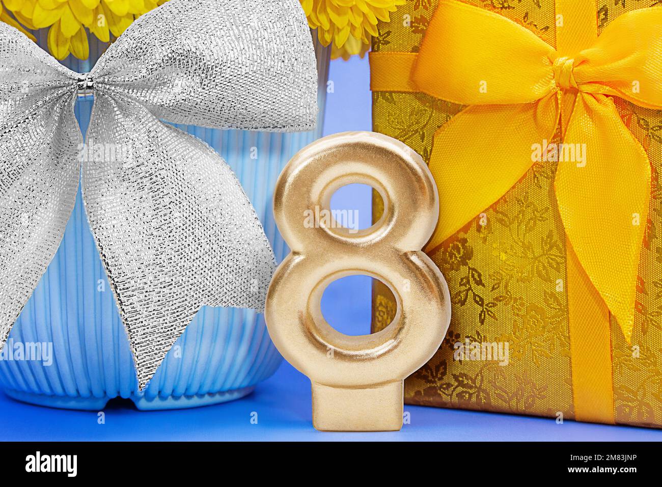 Numéro d'or 8 avec boîte-cadeau jaune brillant et fleur en pot bleu et noeud argenté. Journée internationale de la femme, 8 mars, anniversaire Banque D'Images