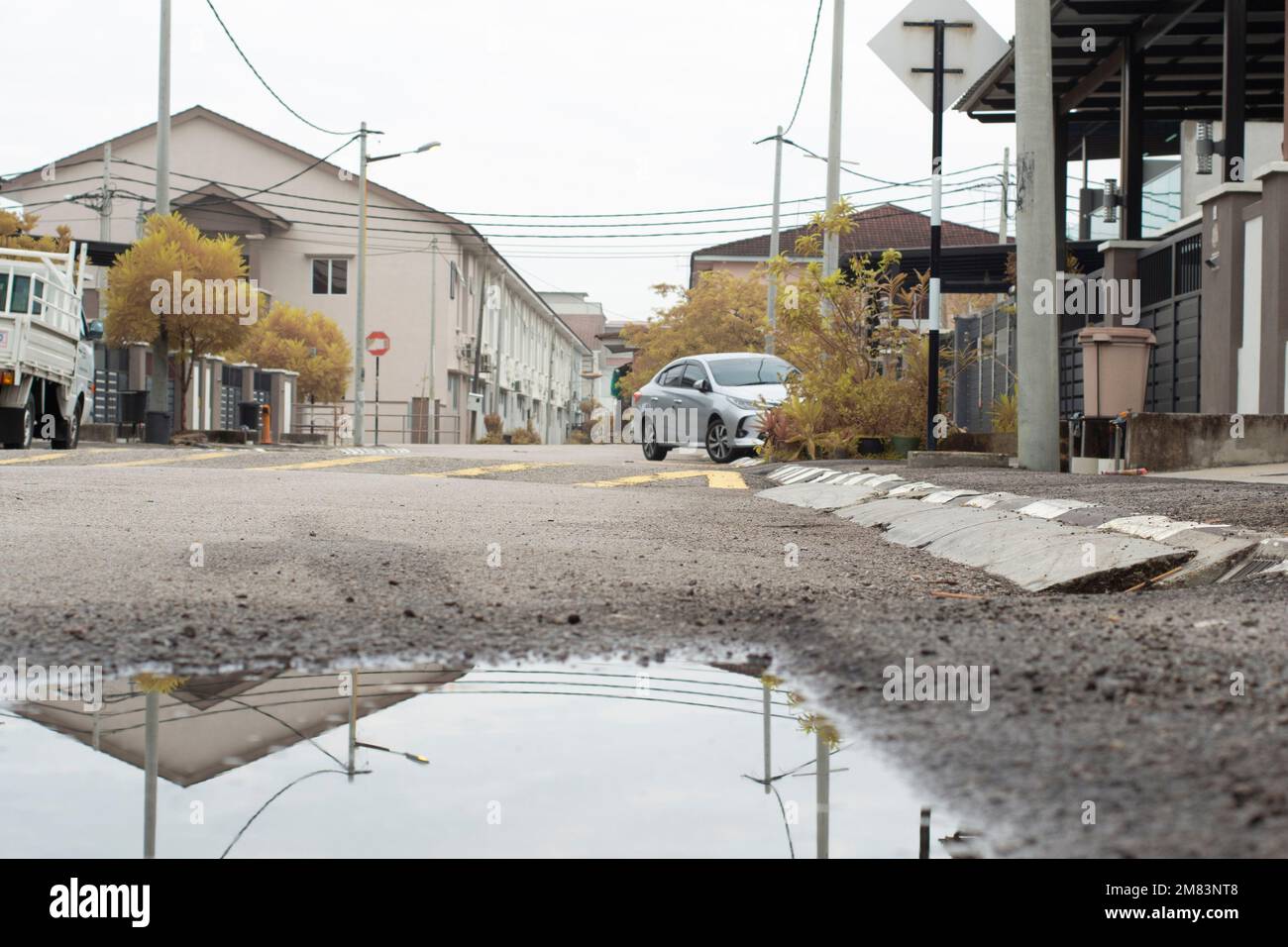 piscine d'eau stagnante après la pluie dans la rue asphaltée de la banlieue Banque D'Images
