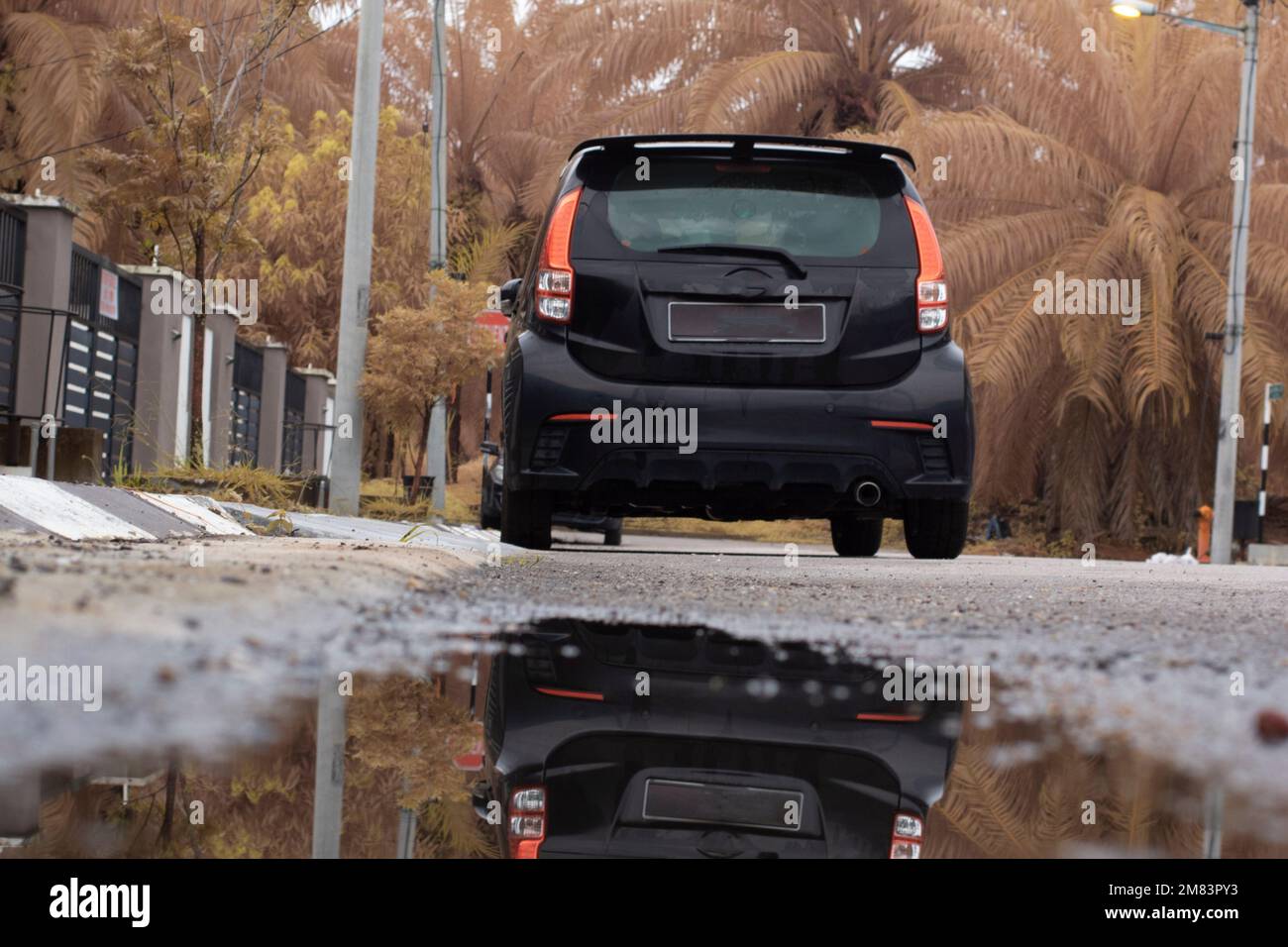 piscine d'eau stagnante après la pluie dans la rue asphaltée de la banlieue Banque D'Images