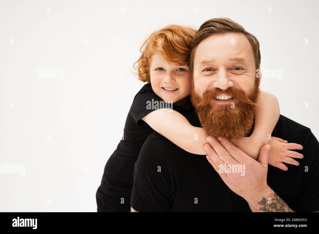 joyeux enfant embrassant grand-père barbu heureux et regardant la caméra isolée sur gris, image de stock Banque D'Images