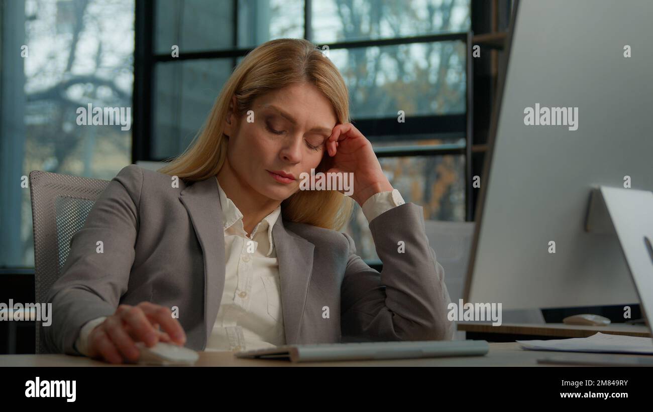 Fatiguée paresseuse adulte d'âge moyen femme gestionnaire employé travailleur s'est ennuyé au travail projet en ligne dans l'ordinateur dans le bureau Caucasien mature malade Banque D'Images