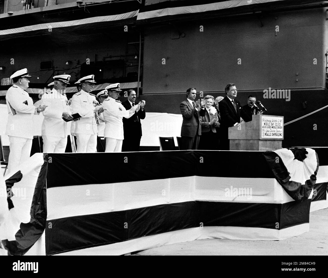 Sen J. Denton Jr., R-Ala, parle du baptême de la BAIE MOBILE de l'Aegis (CG-53). Derrière lui se trouvent (G-D) : sous-amiral W. Meyer, commandant adjoint, systèmes de combat, Commandement des systèmes de la mer navale; CAPT. G. Dowell III, superviseur de la construction navale, de la transformation et de la réparation; Commodore J. Shaw, Gestionnaire de programme, Aegis Shipbuilding, Commandement des systèmes de la mer navale; vice-SMA J. Metcalf III, chef adjoint des opérations navales, guerre de surface; M. Knecht, M. J. St. PE»; Jane Denton, commanditaire; M. McPhillips, matron d'honneur; Et Mgr O. Lipscomb. Base: Pascagoula État: Mississippi (MS) cou Banque D'Images