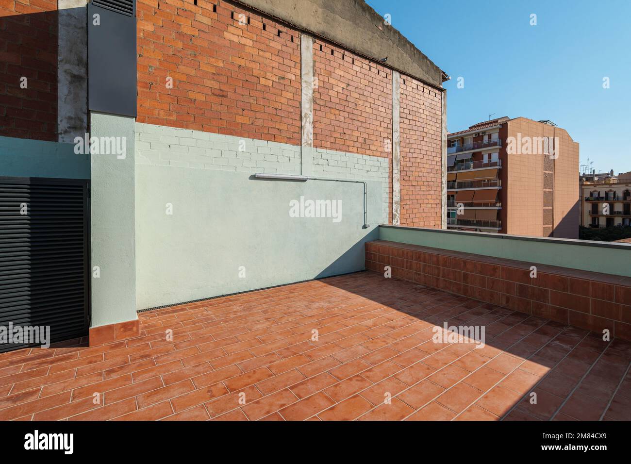 Une grande terrasse vide au deuxième étage d'une grande maison avec un plancher de brique rouge pour se détendre les chaudes soirées d'été au soleil du passage Banque D'Images