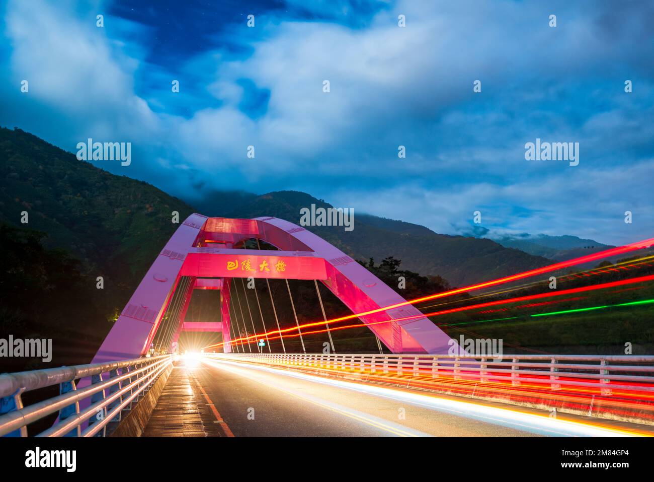 Nuages blancs en mouvement rapide. Photographie lente des phares sur pont rouge. Le pont de pressage est situé sur la Beiheng Highway. Taoyuan City, Taïwan Banque D'Images