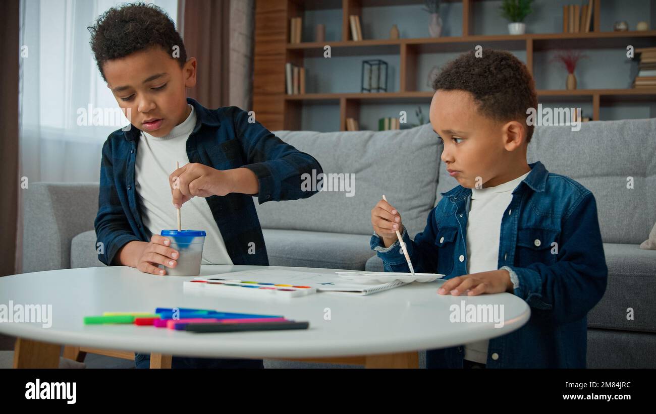 Deux frères enfants afro-américains enfants enfants ethnie fils frère peinture à la maison avec acrylique aquarelle couleurs petits garçons écoliers Banque D'Images