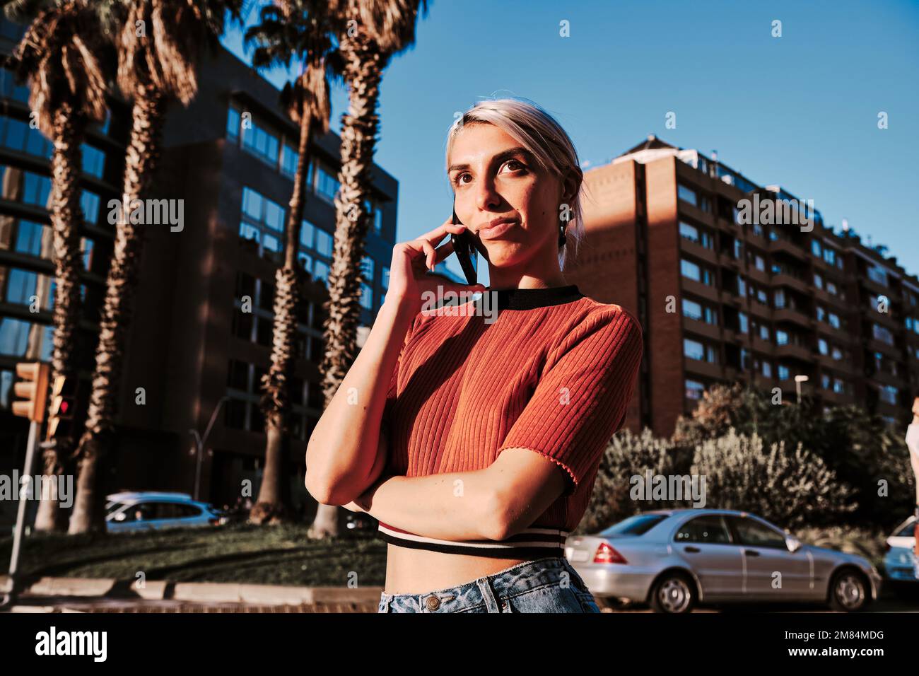 Femme regardant loin en parlant au téléphone debout à l'extérieur. Banque D'Images