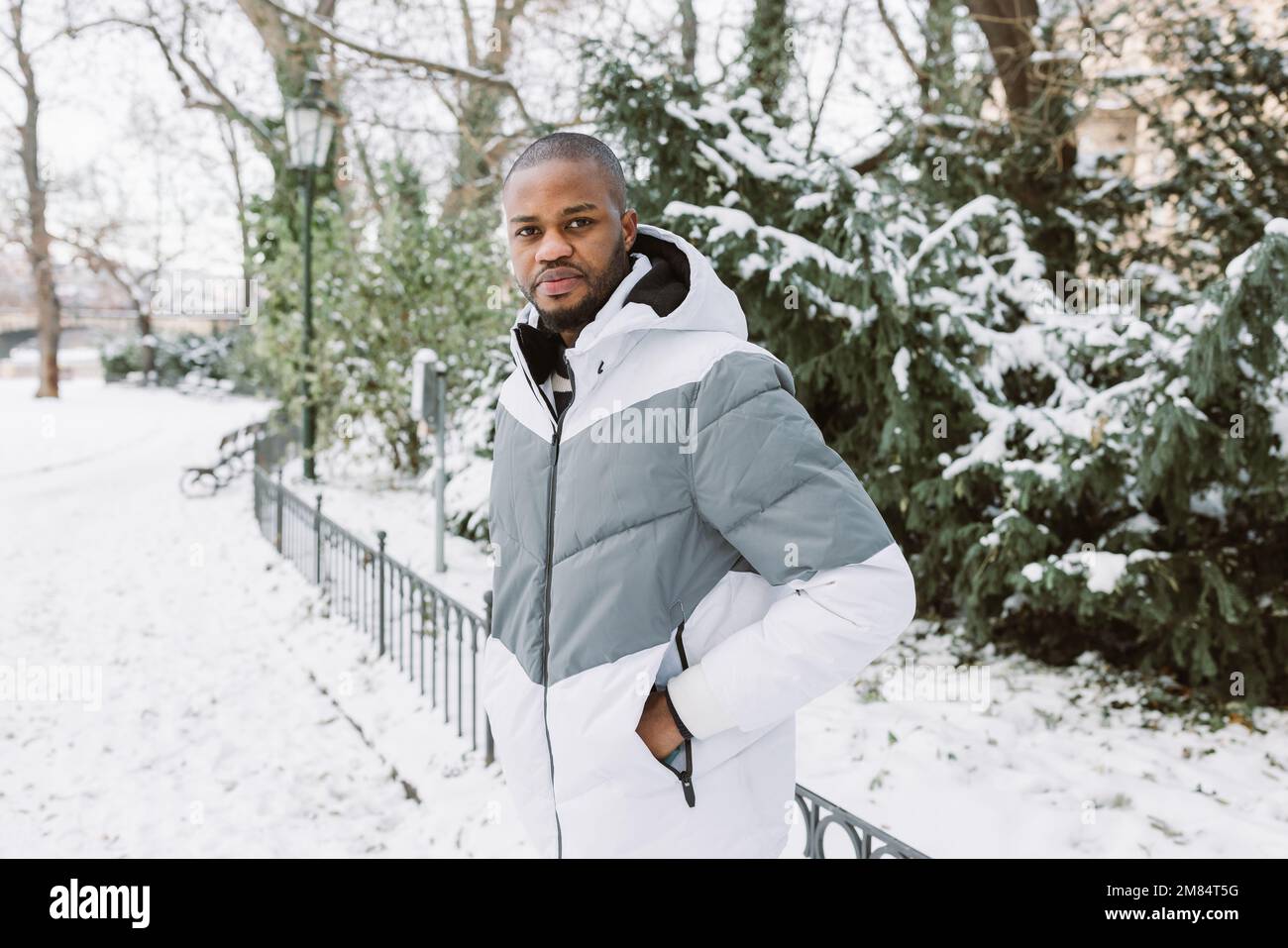 Jeune homme africain dans des vetements decontractes blancs et gris veste de sport. Portrait de rue de la saison d hiver dans le parc avec de la neige. Style de vie concept de