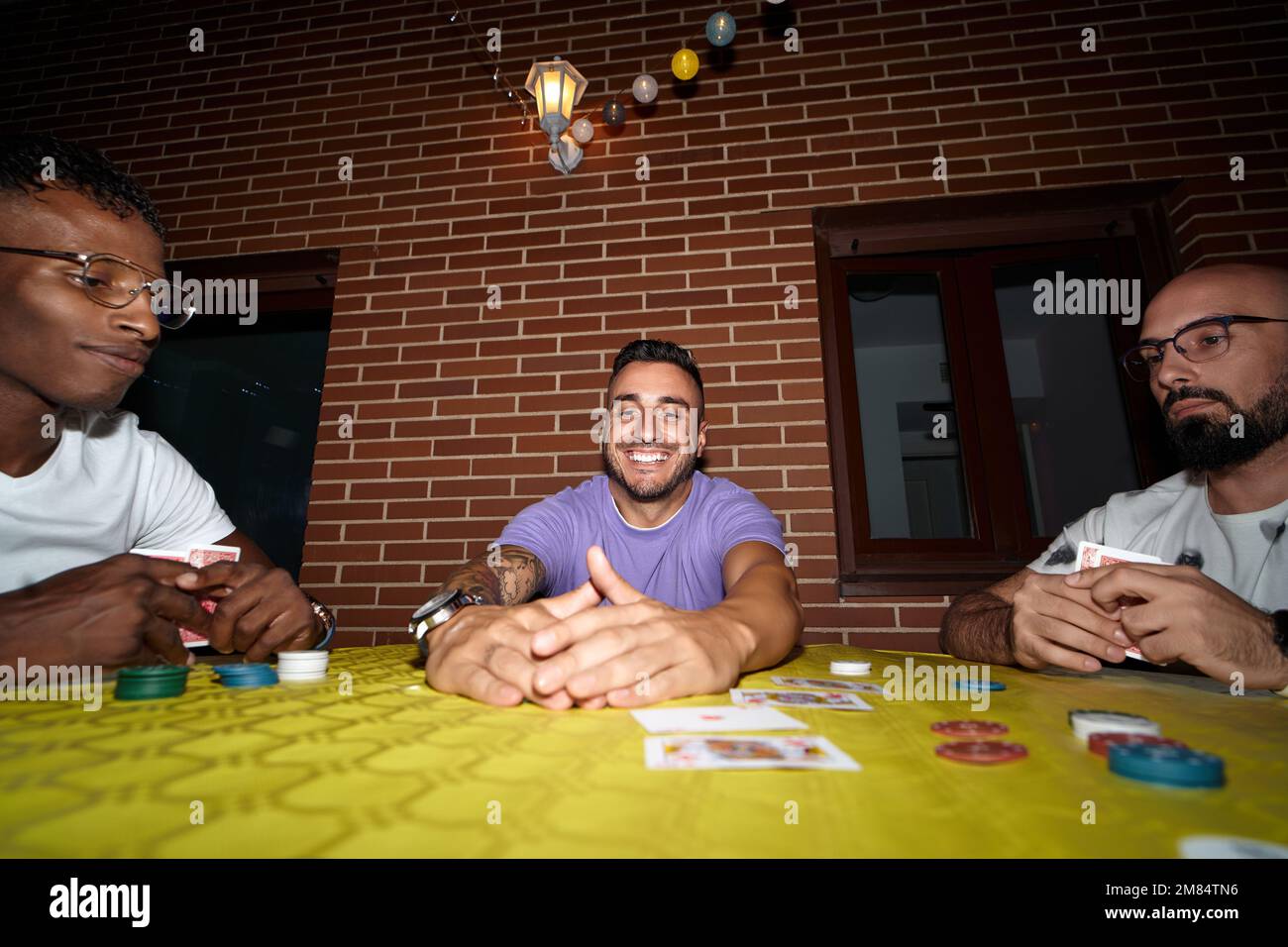 L'homme heureux et excité gagne dans le jeu de cartes de poker tout en jouant avec des amis. Banque D'Images