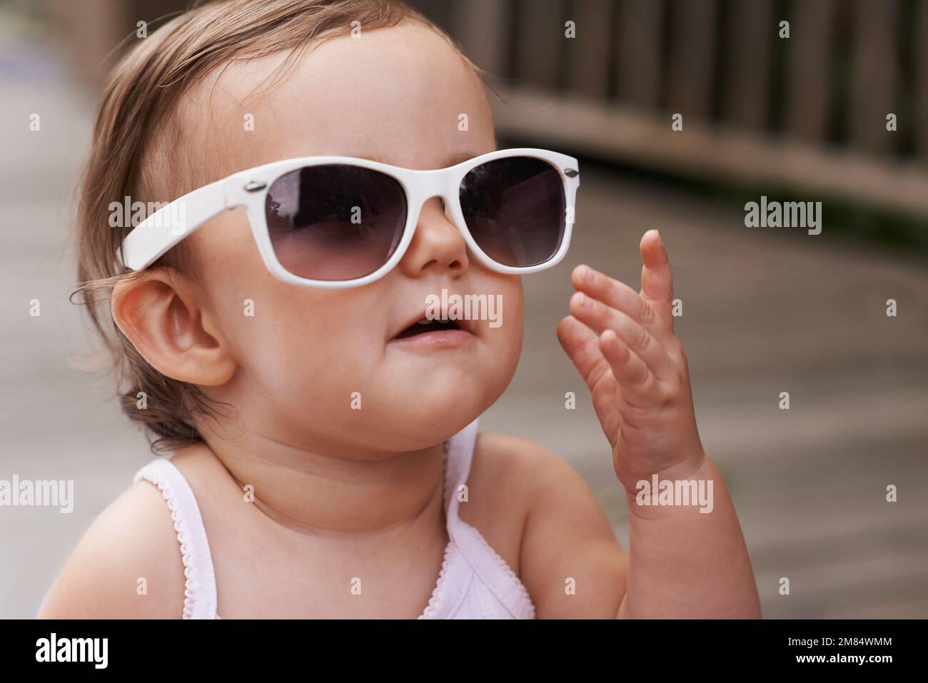 Aimer la mode d'un jeune âge. Une adorable petite fille portant de grandes lunettes de soleil à l'extérieur. Banque D'Images