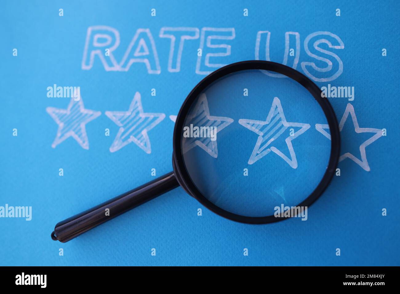 Les commentaires de cinq étoiles nous ont donné une note sur fond bleu avec loupe Banque D'Images Les commentaires de cinq étoiles nous ont donné une note sur fond bleu avec loupe Banque D'Images
