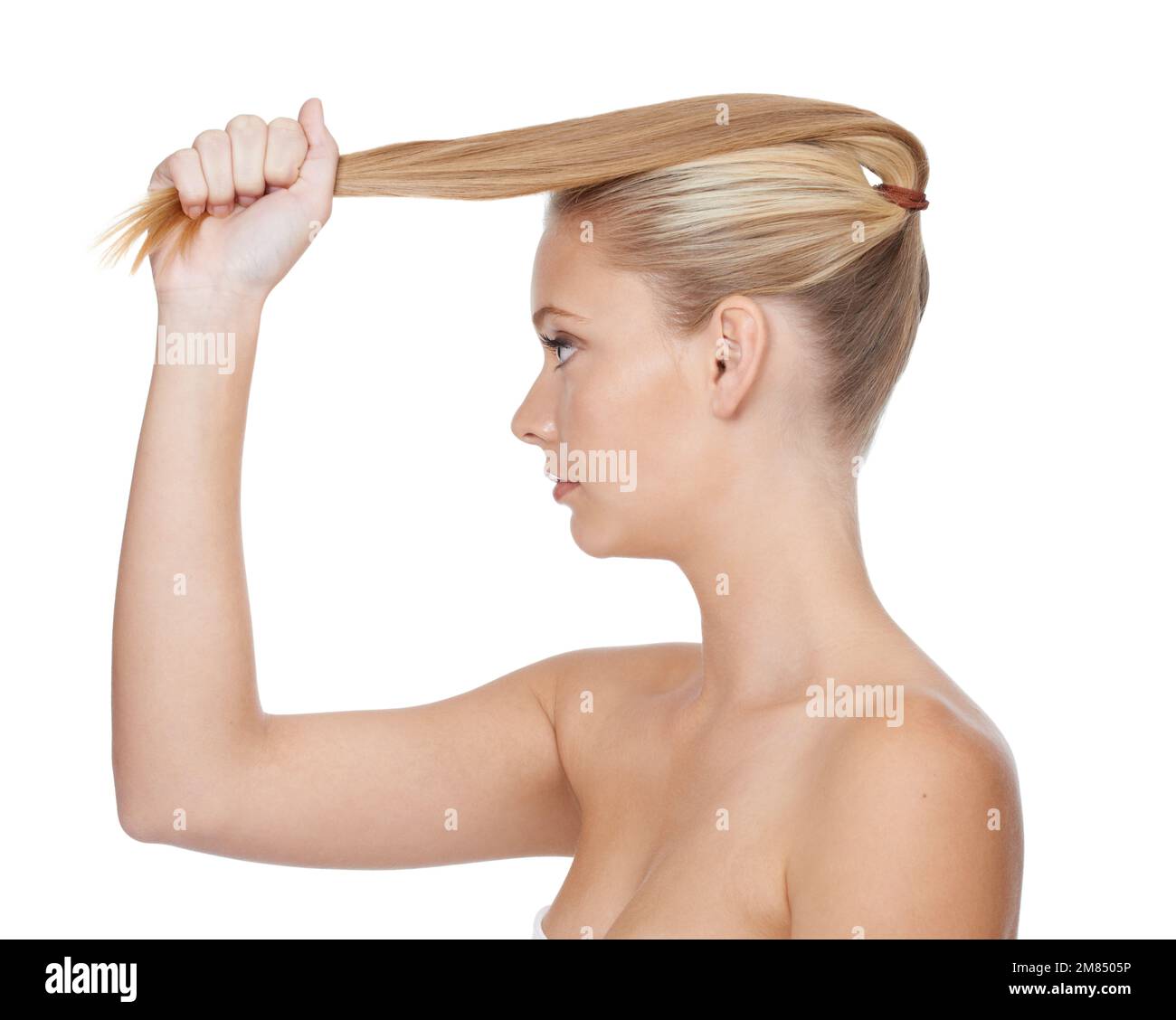 Cheveux tellement forts et naturels. Photo de profil studio d'un modèle blond tirant sur sa queue de cheval isolée sur blanc. Banque D'Images