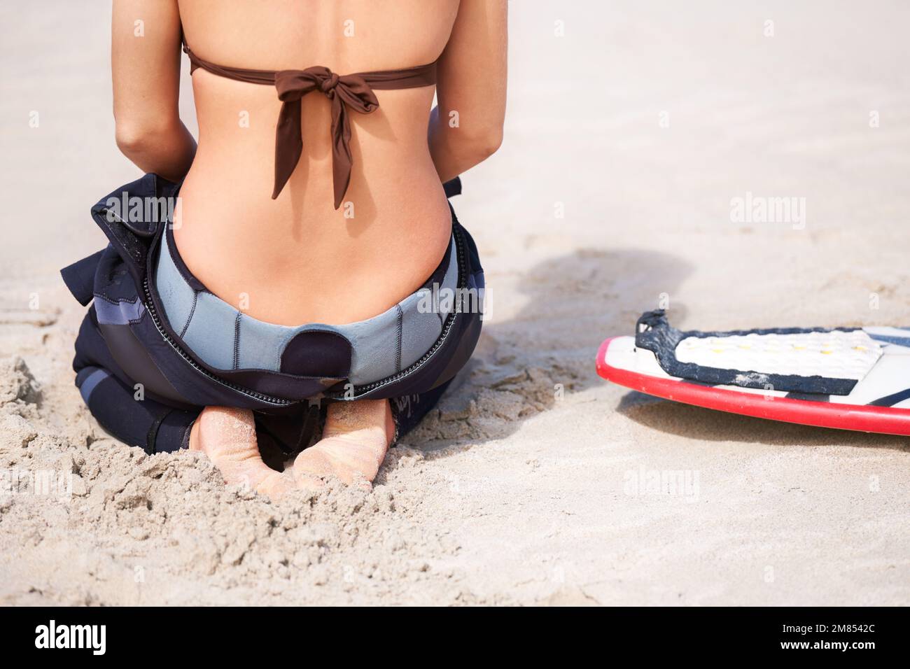 Elle a hâte de frapper l'eau. Une jeune surfeuse se prépare à sortir et à profiter des vagues lors d'une chaude journée d'été. Banque D'Images