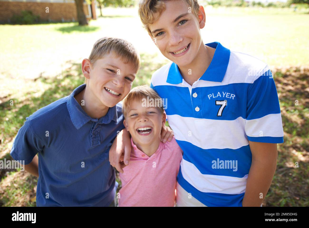 Amour fraternel. Trois frères embrassant et souriant à la caméra. Banque D'Images