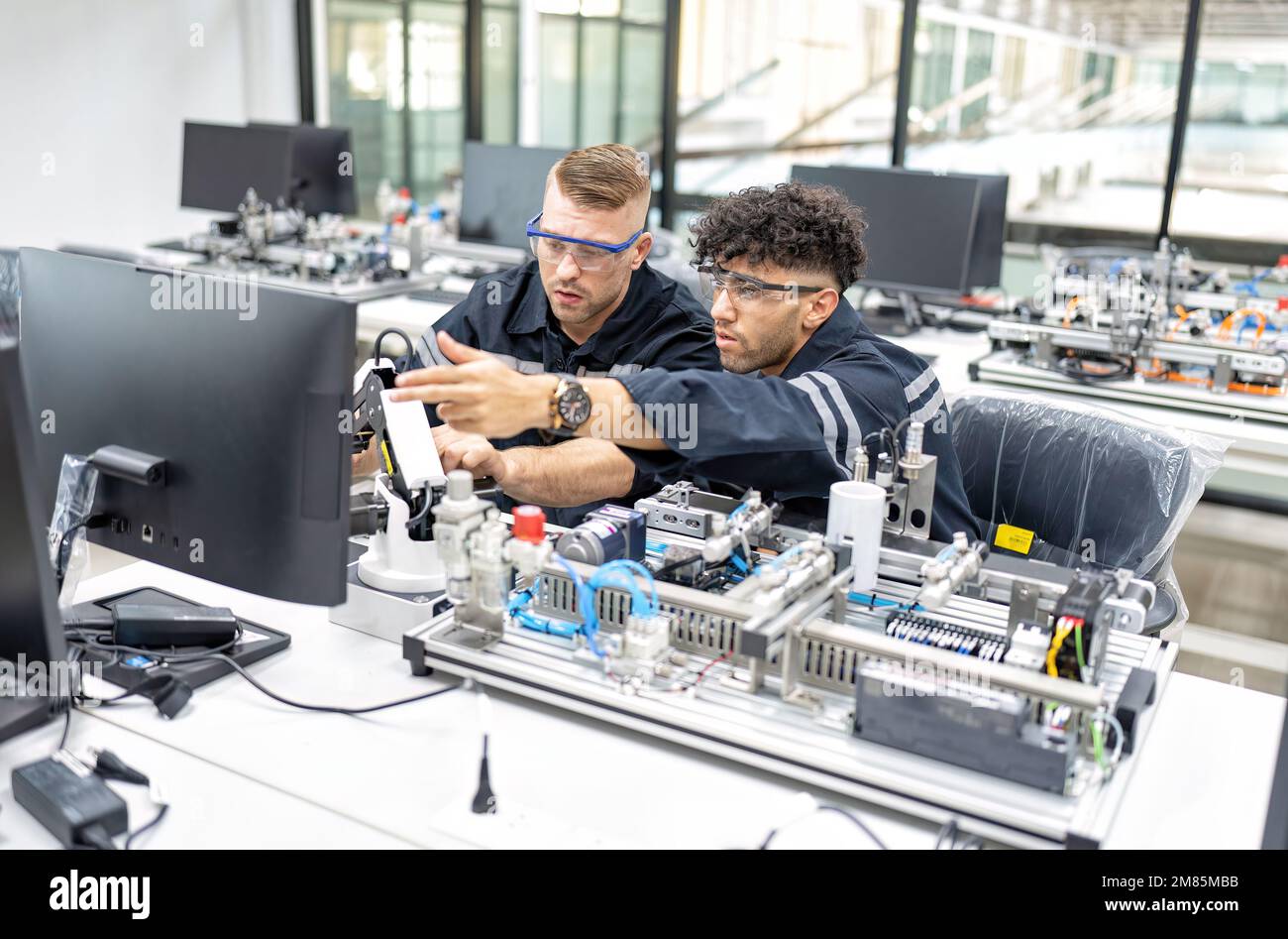 Ingénieur assis dans la salle de fabrication des robots pour vérifier la qualité de l'ingénierie des cartes de commande électroniques Banque D'Images