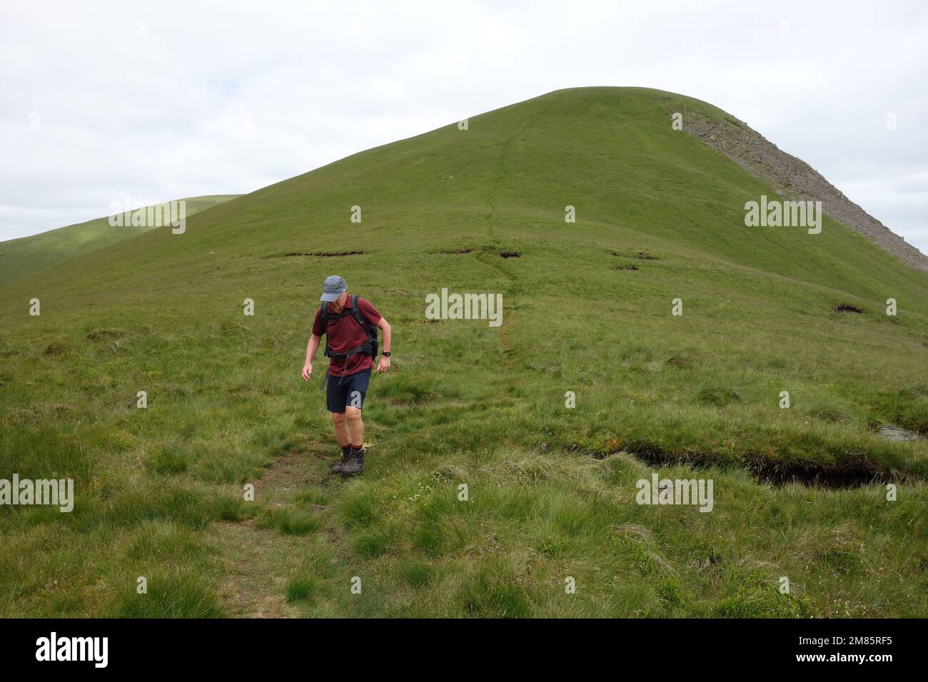 Homme descendant vers la selle de 'Kenssgriff' à 'Yarlside' dans les collines de Howgill près de Sedbergh dans le parc national de Yorkshire Dales, Angleterre, Royaume-Uni. Banque D'Images