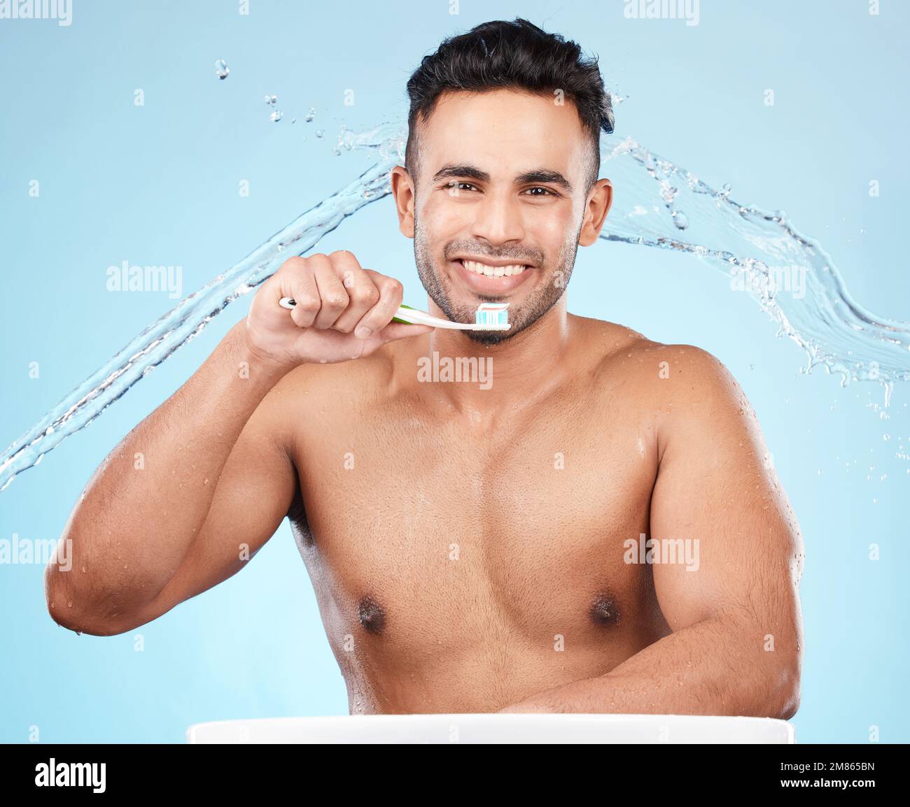 Dents, soins dentaires et éclaboussures d'eau, homme avec brosse à dents et dentifrice sur fond bleu avec sourire sur le visage. Matin, soins de santé et frais Banque D'Images