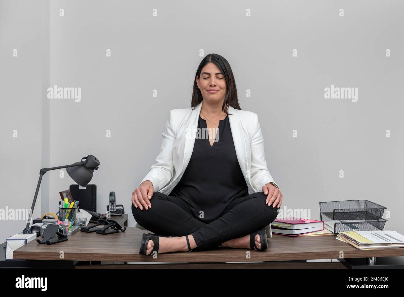 Jeune femme d'affaires méditant sur la fleur de lotus, à son bureau tout en prenant une pause de travail. Femme dans les vêtements d'affaires méditant dans le bureau. Banque D'Images