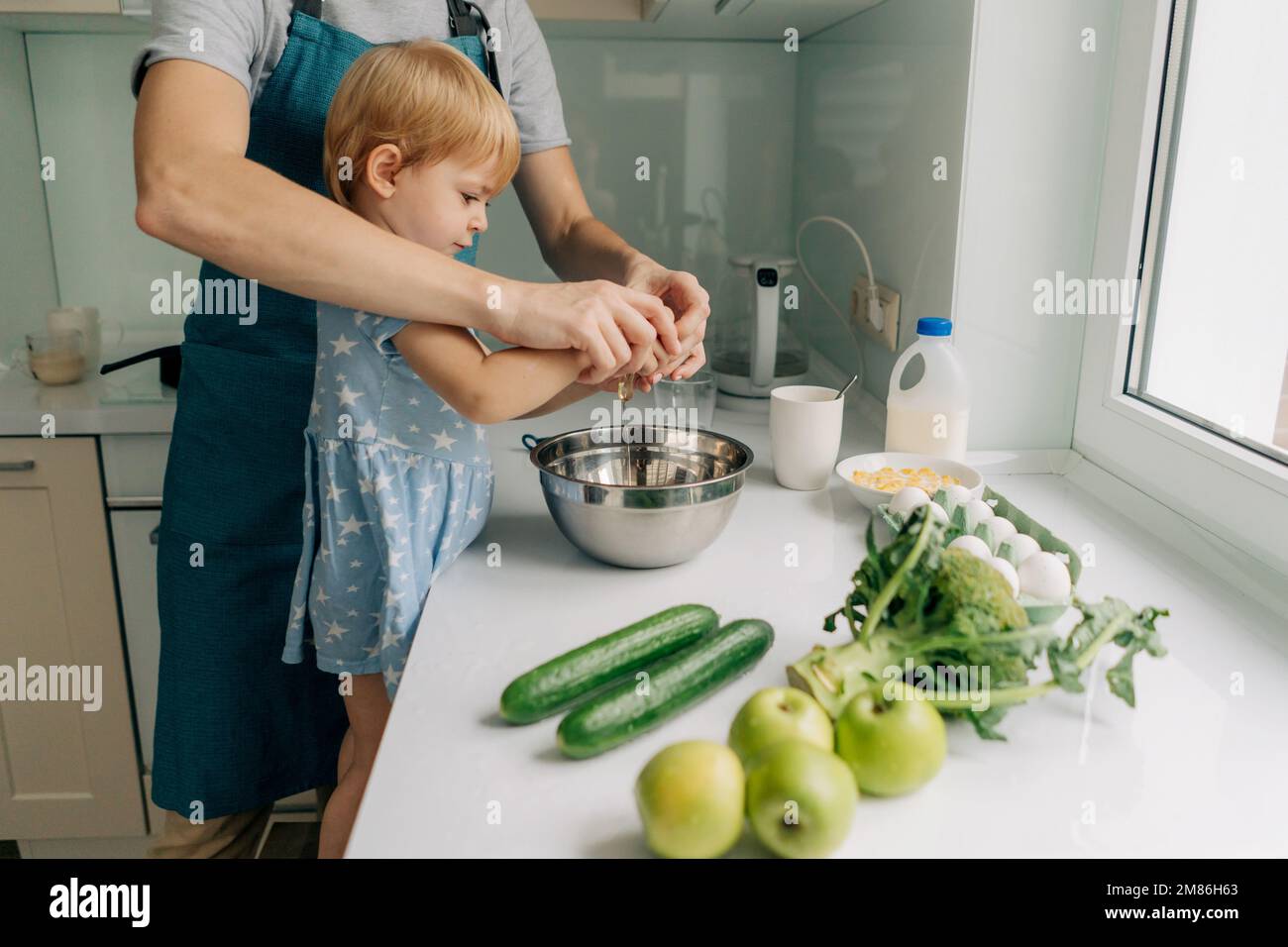 Maman enseigne à sa petite fille comment cuisiner le dîner. Banque D'Images