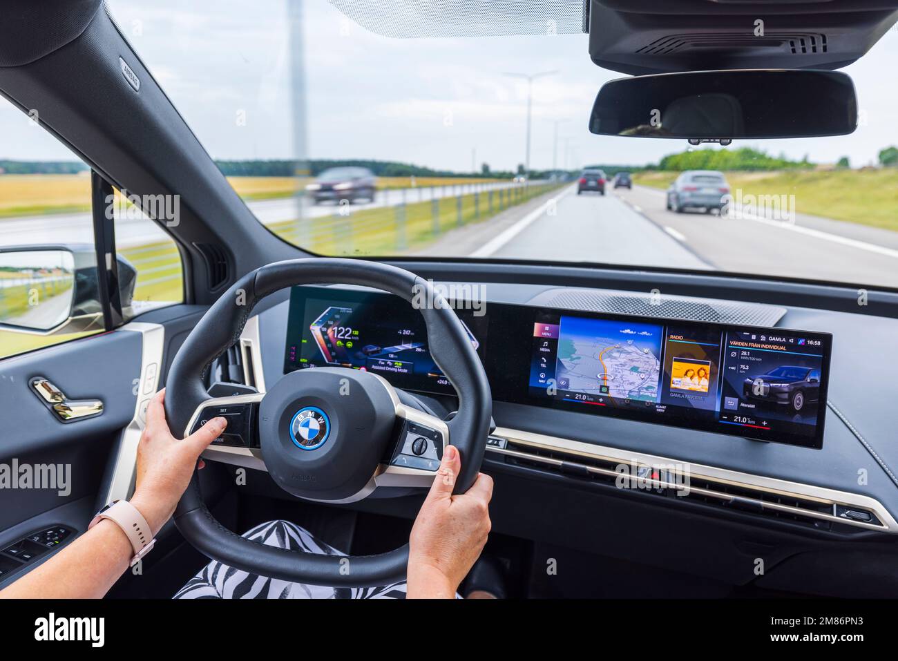 Belle vue intérieure de la voiture électrique BMW iX40 sur la route. Conducteur femelle dans le véhicule. Suède. Banque D'Images