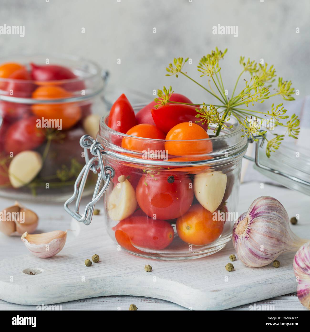 Conserver les tomates fraîches et marinées, les assaisonnements et l'ail sur une table en bois blanc. Aliments fermentés sains. Légumes en conserve à la maison. Banque D'Images