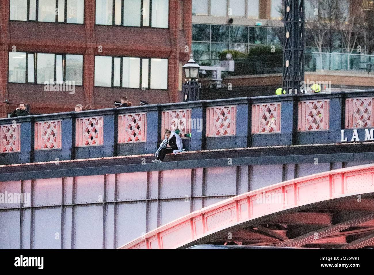 Londres, Royaume-Uni. 12th janvier 2023. La femme peut être vue sur le rebord extérieur du pont, avec une grande présence de ambulanciers paramédicaux, de travailleurs des services de sauvetage, de la police et d'autres personnes sur le pont derrière, ainsi que sur la Tamise. Le pont Lambeth à Westminster a été fermé pendant plusieurs heures cet après-midi et le soir alors qu'une femme avait grimpé sur les chemins de fer, avec l'intention possible de sauter dans la rivière. Tandis que les services de secours de la police patrouillaient la rivière, des navires de fret et certains bateaux à passagers passaient encore sous la rivière. Credit: Imagetraceur/Alamy Live News Banque D'Images