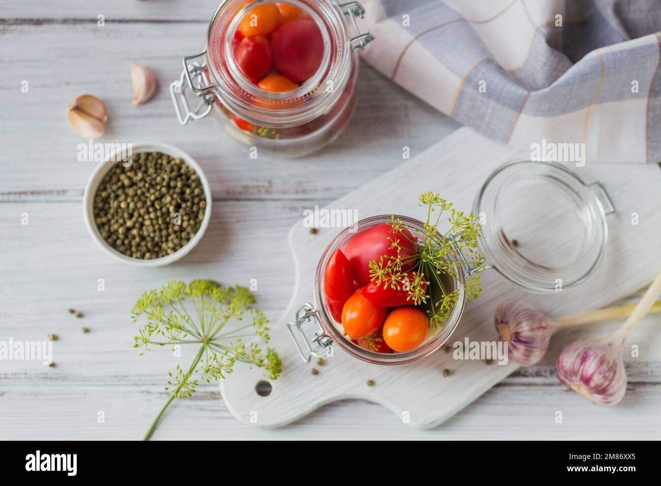 Conserver les tomates fraîches et marinées, les assaisonnements et l'ail sur une table en bois blanc. Aliments fermentés sains. Légumes en conserve à la maison. Vue de dessus Banque D'Images
