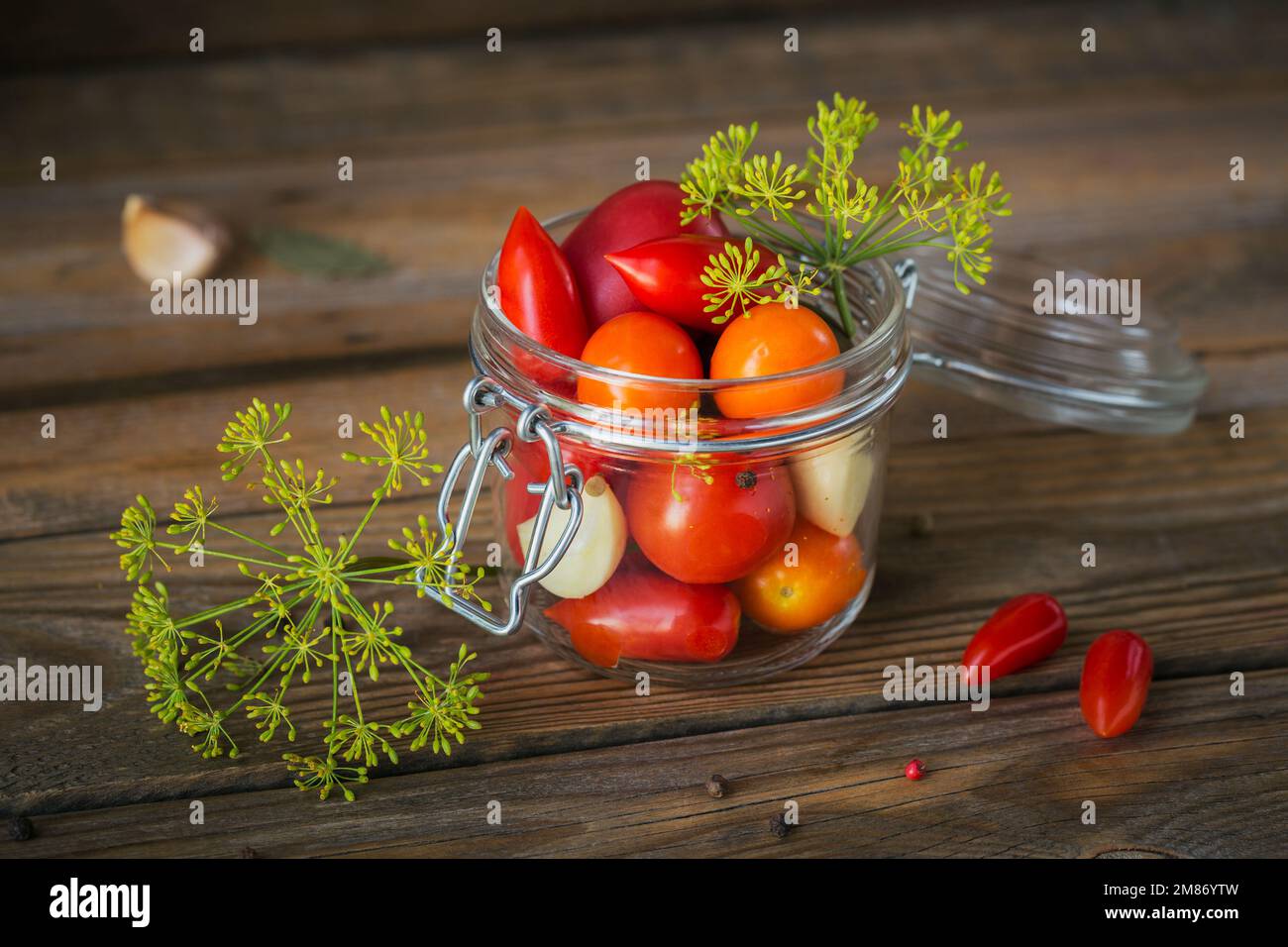 Conserver les tomates fraîches et marinées, les assaisonnements et l'ail sur une table en bois. Aliments fermentés sains. Légumes en conserve à la maison. Banque D'Images