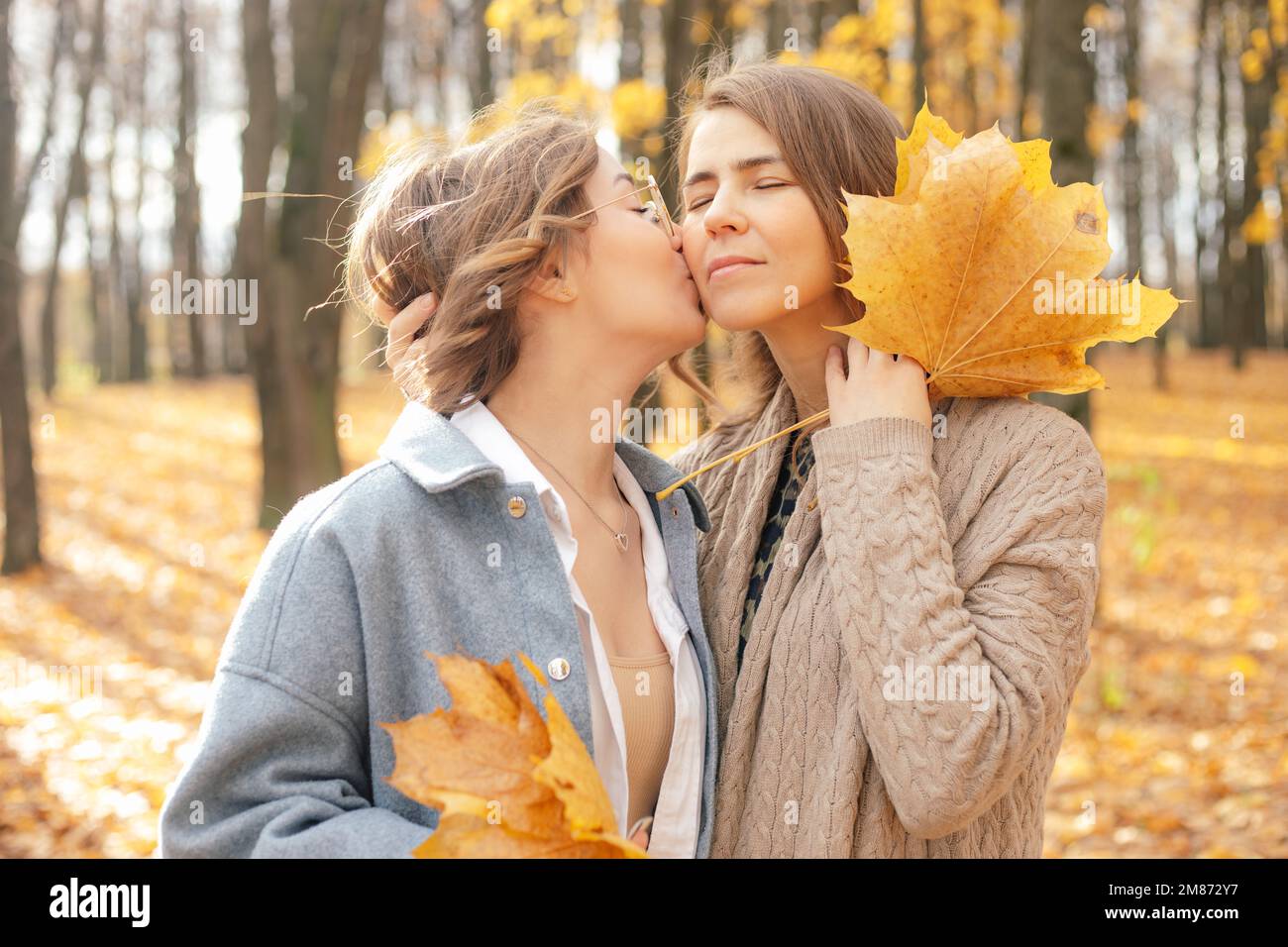 Belle famille belle de mère et de fille s'amusant ensemble, embrassant et embrassant sur les vacances, recueillir les feuilles dans la forêt Banque D'Images