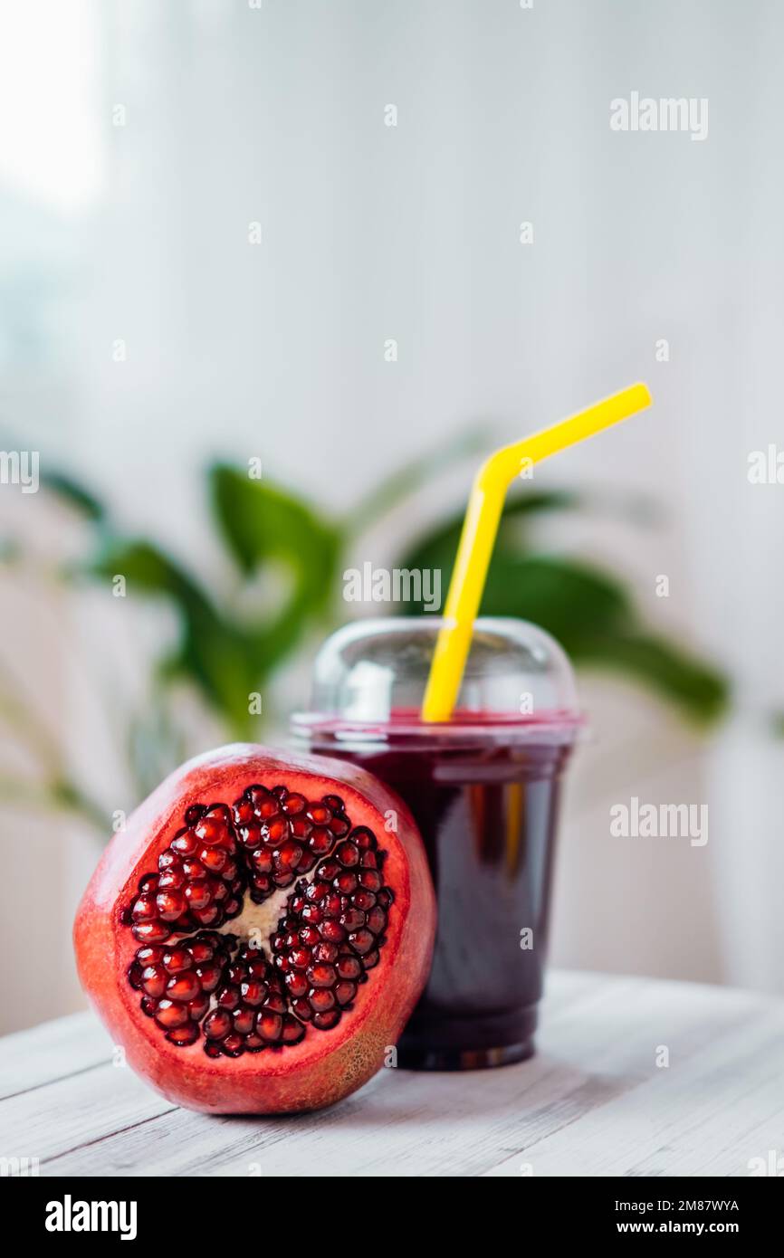 Jus de fruits frais. Jus de grenade coloré à emporter dans un verre en plastique. Banque D'Images