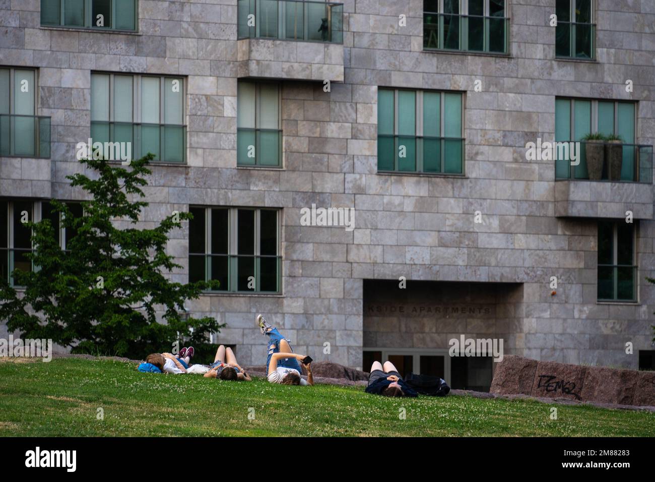 Quatre jeunes filles allongé sur l'herbe verte sur leur dos devant une maison résidentielle; amis prenant une sieste ensemble à l'extérieur Banque D'Images