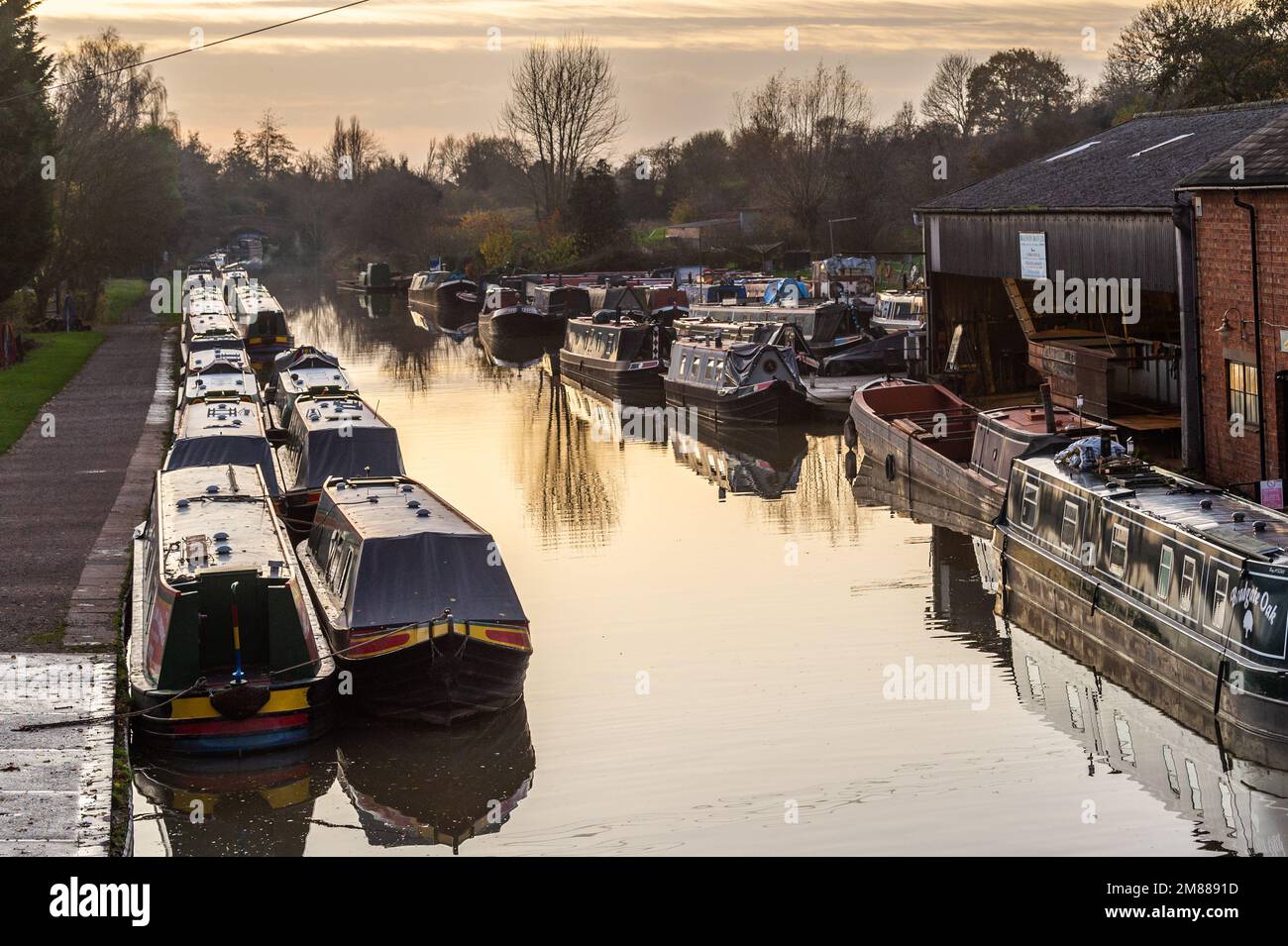 Des bateaux-canaux amarrés sur le Grand Union Canal au coucher du soleil à Braunston, Northamptonshire, Royaume-Uni. Banque D'Images